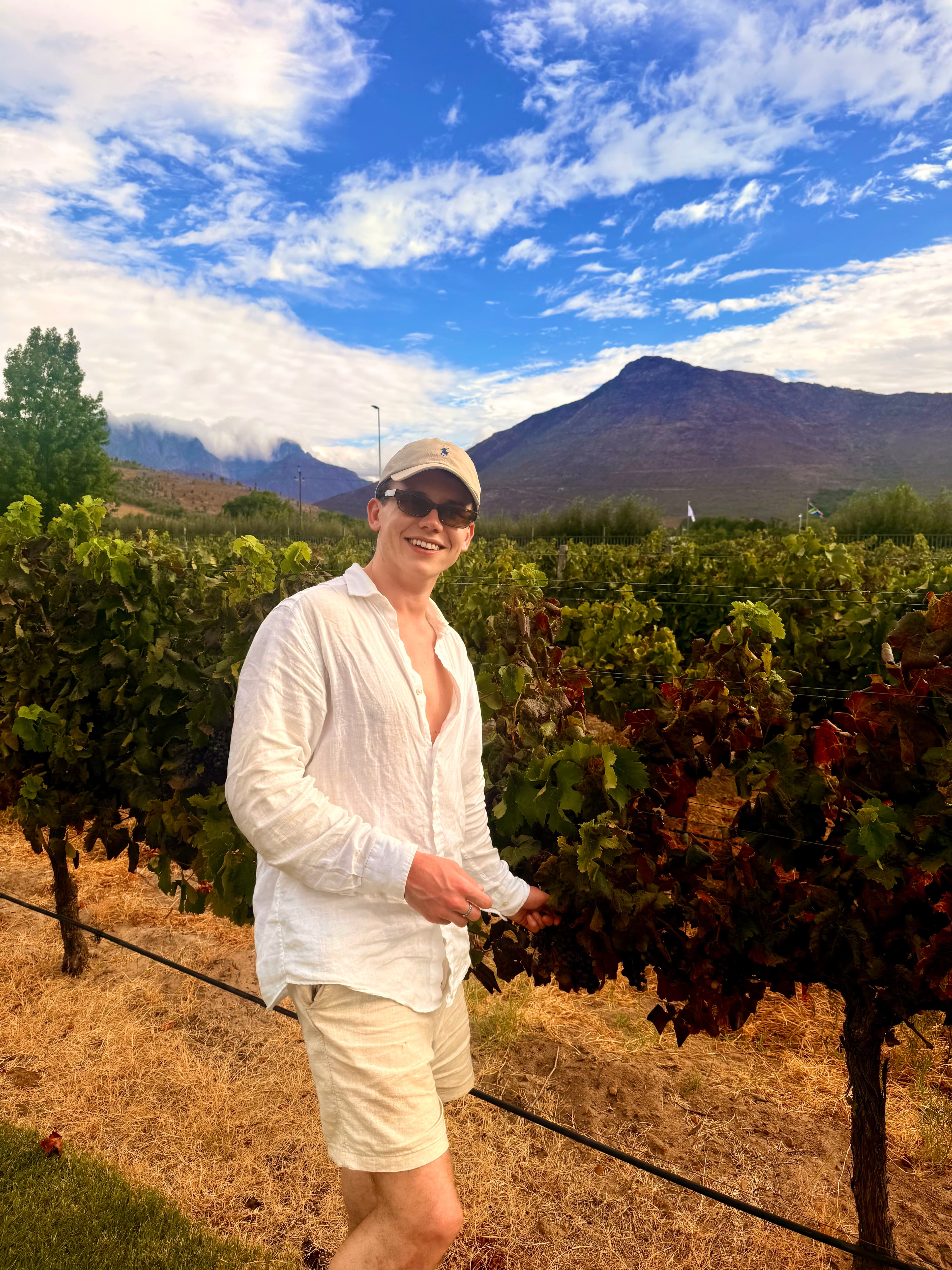 Alex in a vineyard with mountain views in South Africa.